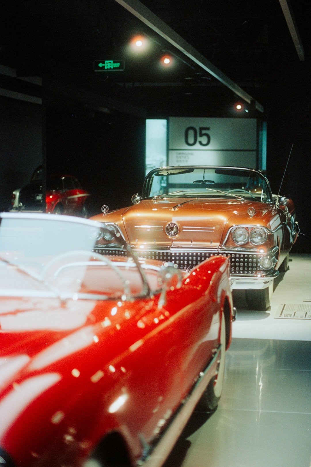 Modern exhibition hall displaying luxury automobiles under dramatic lighting